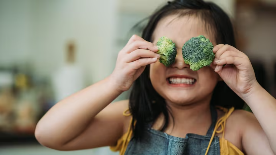 Petite fille qui s'amuse avec du brocoli, comprenant qu'il est accepté dans son alimentation